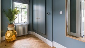 A room with a large window, a radiator, a potted plant, and a wardrobe. - Wansfell at Lipwood House (Windermere)