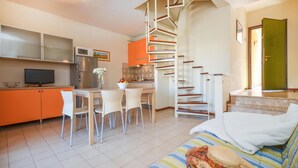 Un espace de vie compact comprenant une cuisine, un coin repas et un escalier.
