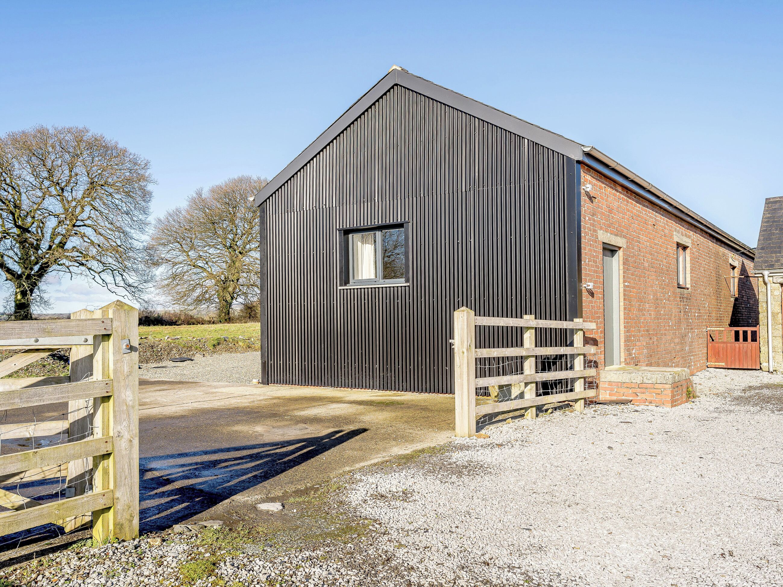 A modern barn with a metal exterior and a wooden gate.