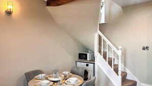 Zona pranzo con tavolo rotondo per quattro persone, forno a microonde e lavatrice sullo sfondo.