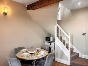 A dining area with a round table set for four, a microwave, and a washing machine in the background.
