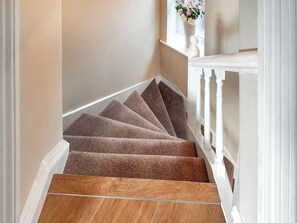 A carpeted staircase with a wooden floor at the bottom, white railings, and a vase with flowers on the landing. - 2 bedroom accommodation in Oakworth, Near Haworth (Oakworth)