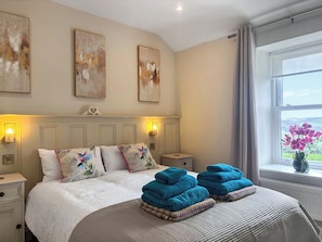 Een slaapkamer met een bed, nachtlampjes, een nachtkastje, een raam met uitzicht en kunst aan de muur.