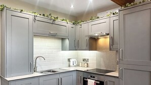A kitchen with grey cabinets, a white tiled backsplash, a stainless steel sink, and a built-in oven.