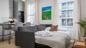 Un dormitorio moderno con cama, sofá, comedor y cocina.