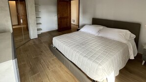 A bedroom with a large bed, wooden flooring, and a wardrobe. - San Donato residence (Montepulciano)