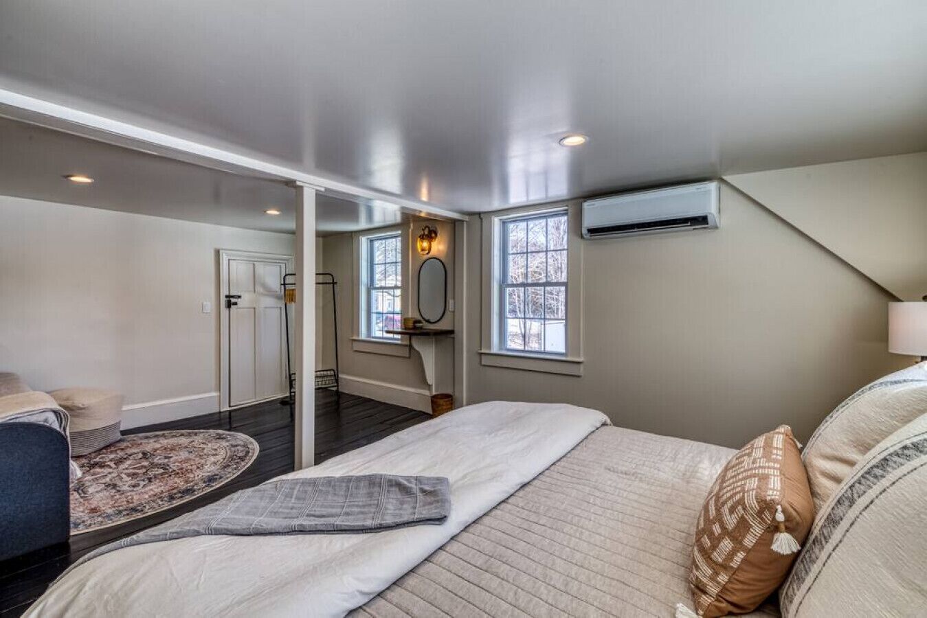 Un dormitorio con cama, espejo y ventana.