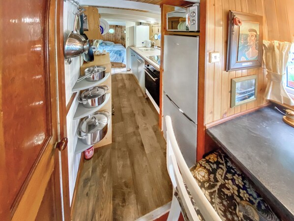 A compact kitchen with wooden cabinets, a refrigerator, a microwave, and a sink.