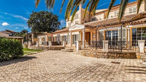 Un patio con pavimento de adoquines, un edificio con tejado de tejas y palmeras.
