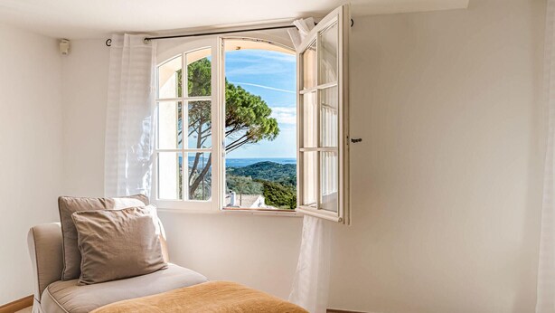 Un dormitorio con un ventanal que ofrece vistas a árboles y colinas.