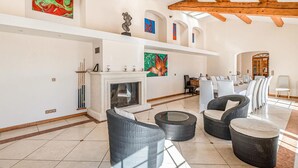 Amplia sala de estar con chimenea, mobiliario de mimbre y obras de arte moderno.