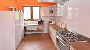 Une cuisine avec des meubles blancs, une cuisinière, un four à micro-ondes et un réfrigérateur.