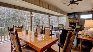 A wooden dining table with chairs, a fireplace, and a TV on the wall.