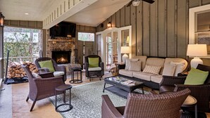 A cozy living room with wicker furniture, a fireplace, and a ceiling fan.