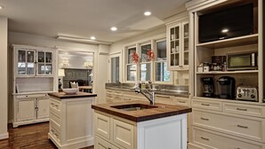 A spacious kitchen with white cabinetry, a wooden countertop island, and a built-in microwave.