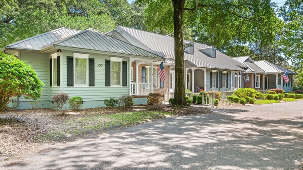 A row of traditional houses with a porch, a driveway, and a well-maintained lawn.