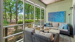 A cozy room with a large window, wicker furniture, and a blue abstract painting. - 3BR/3BA Ground Level ,Gated Pawleys Plantation (Pawleys Island)