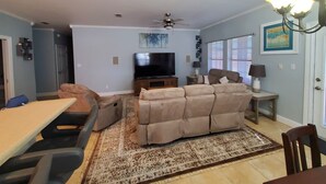 Una sala de estar con sofá, televisor y un comedor con mesa y sillas.