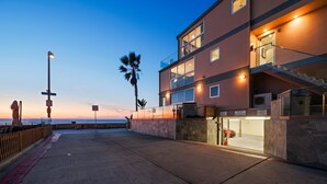Un edificio frente a la playa con fachada de piedra, varios balcones y vista despejada del océano.