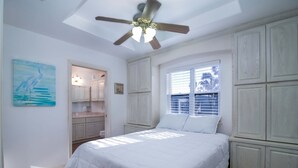 A bedroom with a bed, a ceiling fan, a window with blinds, and a painting on the wall. - Coastal Breeze - Waterfront, Pools, Golf, Tennis (Port Isabel)