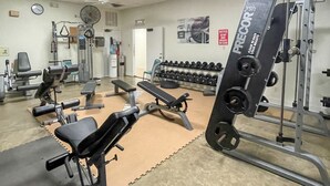 A gym with weightlifting equipment, benches, and dumbbells. - Coastal Breeze - Waterfront, Pools, Golf, Tennis (Port Isabel)