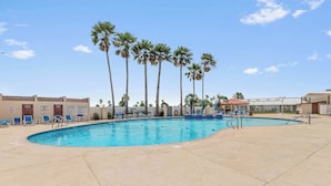 A swimming pool with palm trees, lounge chairs, and a lifeguard stand. - Coastal Breeze - Waterfront, Pools, Golf, Tennis (Port Isabel)
