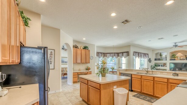 A spacious kitchen with wooden cabinets, a black refrigerator, a central island, and a trash can. - Large executive 4 Bed Villa w/pool & spa, set in peaceful community. Near WDW (Davenport)