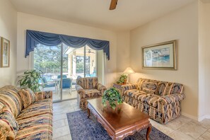A spacious living room with a large window, a ceiling fan, and a view of the outdoors.