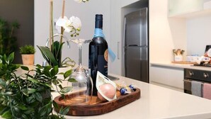 Eine Küchenarbeitsplatte mit einer Weinflasche, einem Glas und einem Holztablett mit Lebensmitteln.