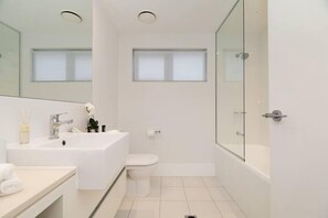 Ein modernes Badezimmer mit Waschbecken, Toilette und Badewanne in Weiß.