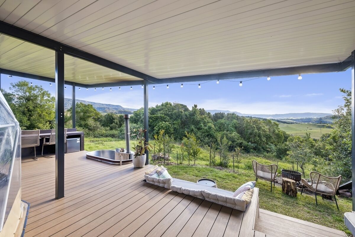 Una terrazza esterna coperta con pavimento in legno, area relax e barbecue.