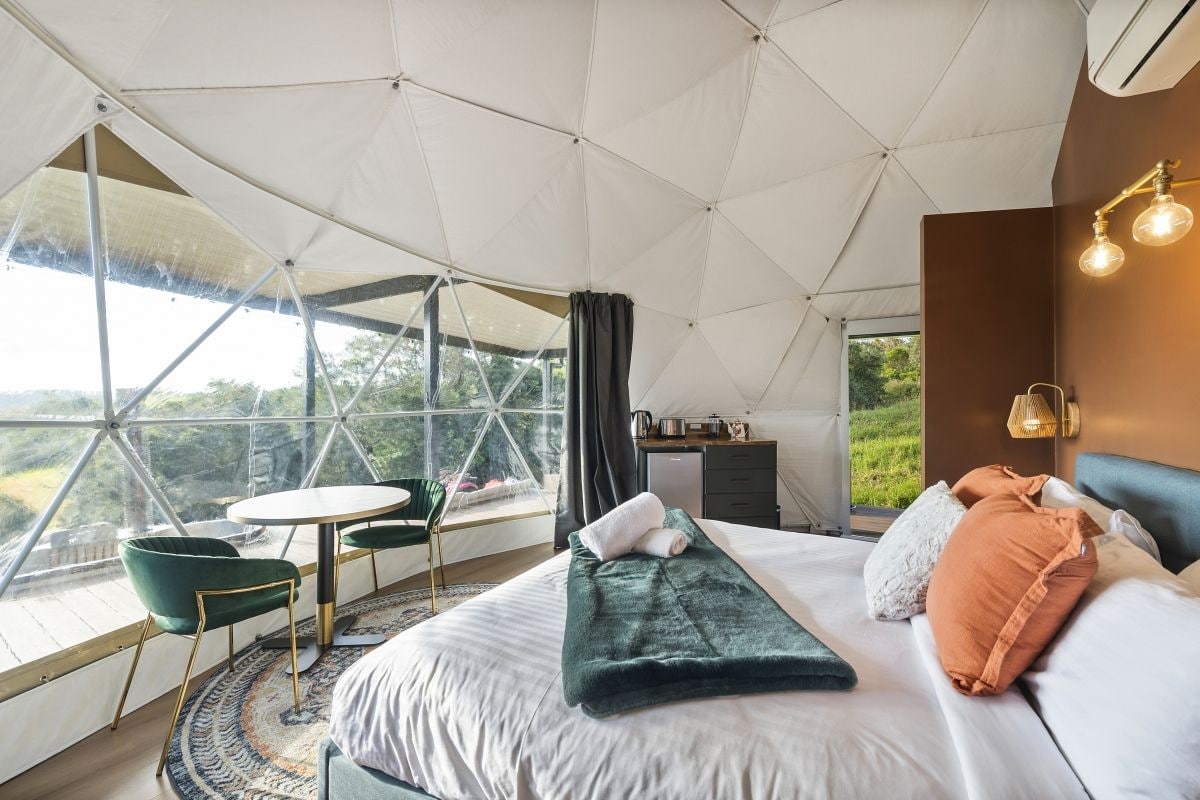A spacious tent-style bedroom with a large bed, a small table, and two chairs.