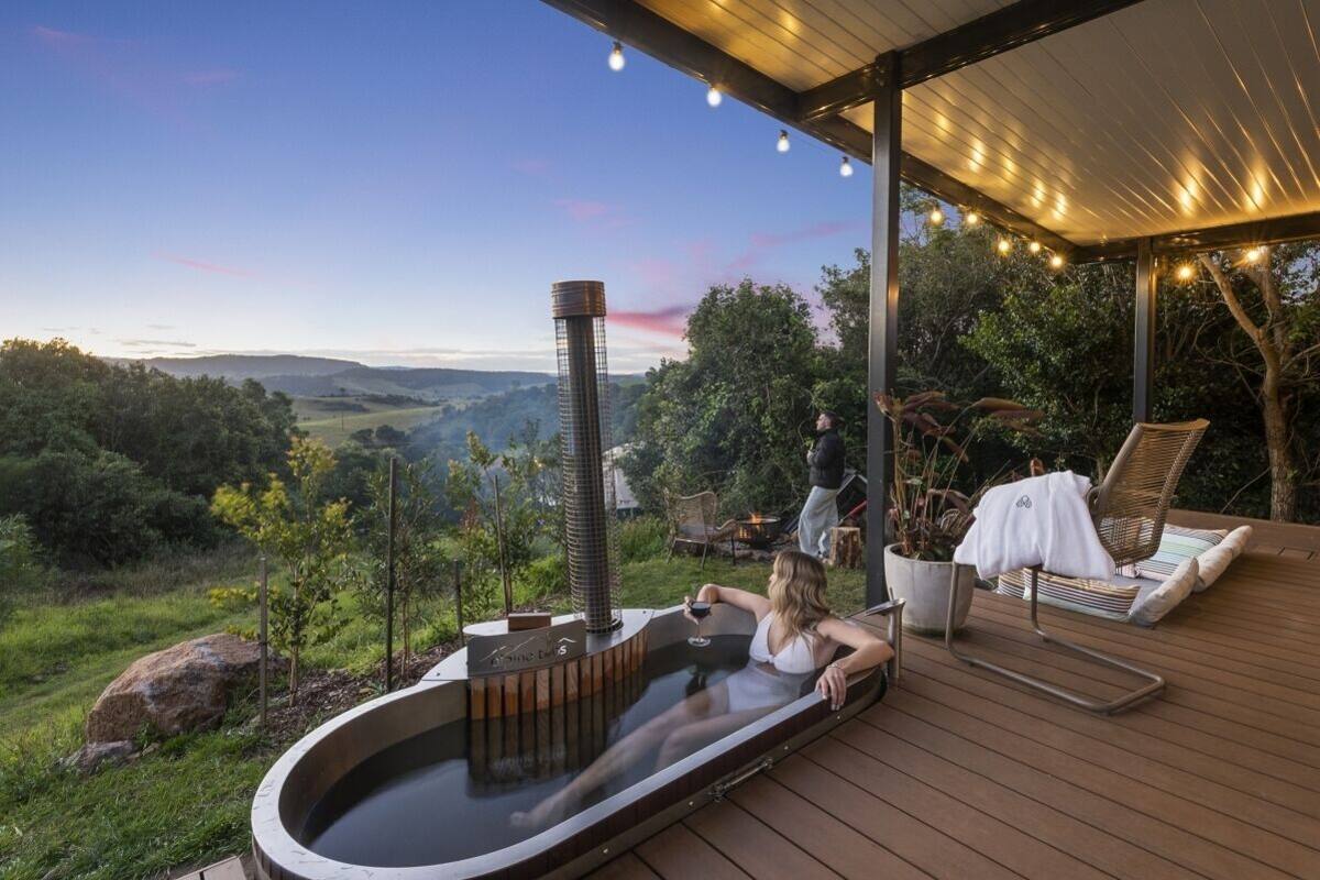 Un jacuzzi en una terraza de madera con vistas panorámicas a colinas y árboles.