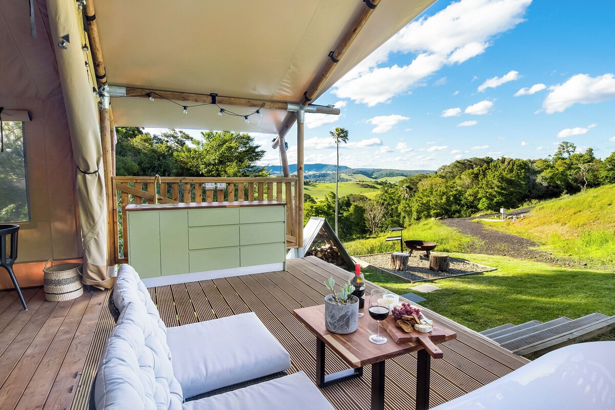 A covered outdoor seating area with a view of a green landscape.