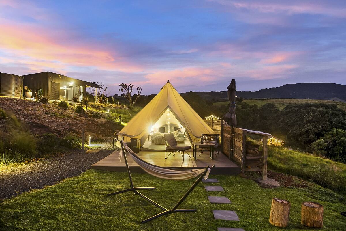 Alojamiento en tienda de campaña con vistas al paisaje circundante, una hamaca y una terraza de madera.