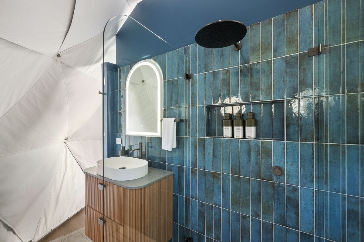 Ein modernes Badezimmer mit einem runden Waschbecken, einem Spiegel und einer Dusche.