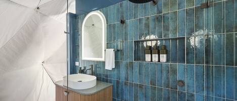 Ein modernes Badezimmer mit einem runden Waschbecken, einem Spiegel und einer Dusche.