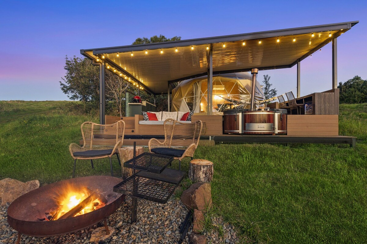 A modern outdoor living space with a fire pit, seating area, and a covered patio.