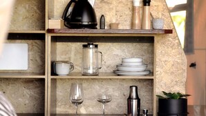 A kitchen with wooden shelves holding various kitchenware, including a coffee maker, a kettle, and a blender. - Cicada Luxury Camping (Jerrara)