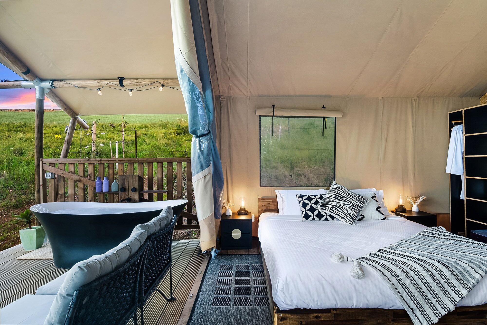 A bedroom with a large bed, a bathtub, and a view of the outdoors.