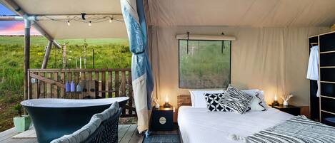 A bedroom with a large bed, a bathtub, and a view of the outdoors.