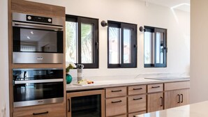 A modern kitchen with built-in appliances, wooden cabinets, and large windows. - Casa Del Mar Las Olas Beachfront 2BR Penthouse (San Jose del Cabo)