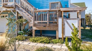 Une maison bleue avec une terrasse en bois et un escalier menant à un balcon.