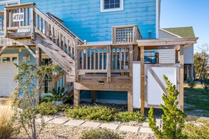 Una casa azul con un porche de madera y escaleras que llevan a un balcón.