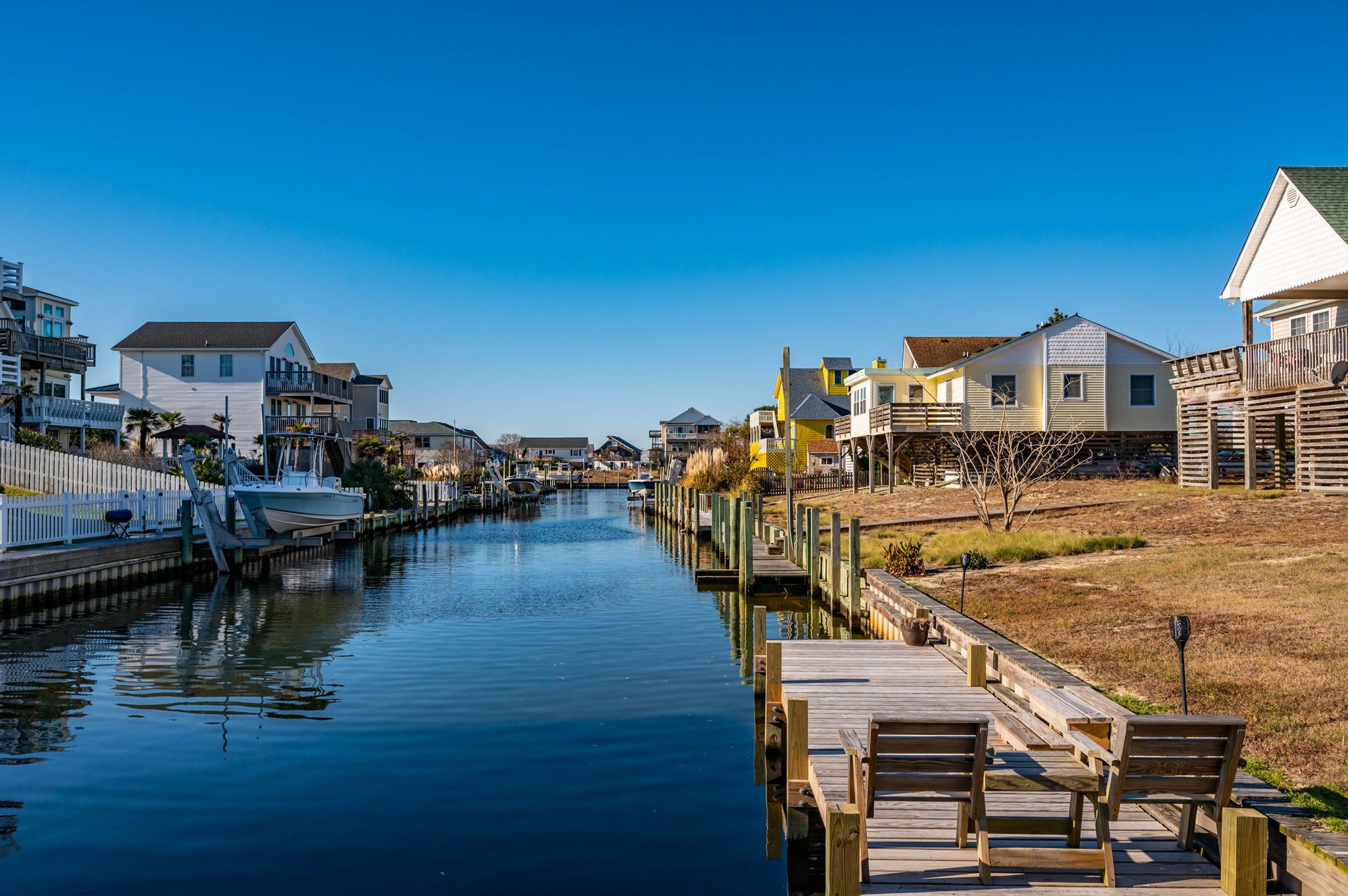 A canal with wooden docks and benches, surrounded by residential buildings with balconies and waterfront views.