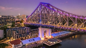 A bridge with illuminated purple lights, a dock area with a sign reading "FELLOWS BREWING CO", and a building with "HSW" on its roof.
