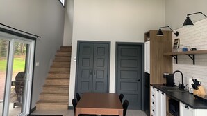 Une cuisine moderne avec un escalier en bois, un coin repas et une vue sur l’extérieur.