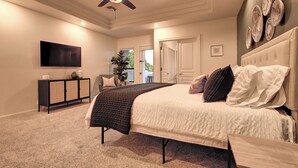 A bedroom with a bed, a television, a ceiling fan, and a door leading to a balcony. - Casa Buena—Luxurious Retreat w/2 Masters & Views! (Phoenix)