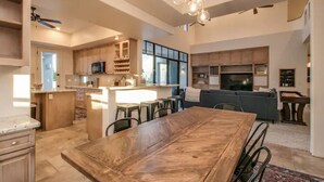 A spacious kitchen with a central island, wooden dining table, and bar stools.
