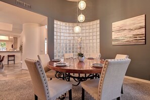 Un comedor con una mesa redonda, sillas y una pared decorativa con diseño de cuadrícula.